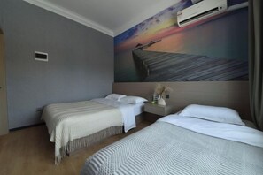 A hotel room with two beds, a painting of a sunset, and an air conditioning unit. - Banyan Tree Villa Hotel (Semporna)