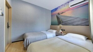 Quarto de hotel com duas camas, uma pintura do pôr do sol sobre um cais e um aparelho de ar condicionado.