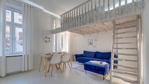 Un salon moderne avec un canapé bleu, une table à manger avec des chaises et une échelle en bois.