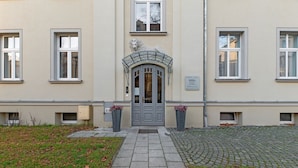 Un bâtiment doté d’une entrée centrale, de deux fenêtres de chaque côté et d’une petite fenêtre sur la droite.
