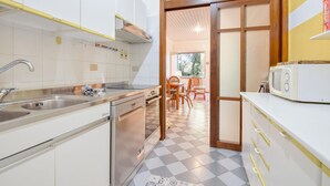 Une cuisine compacte équipée d’un évier, d’une cuisinière et d’un four à micro-ondes. Un coin repas avec une table et des chaises est également disponible.