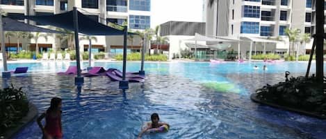 A swimming pool area with lounge chairs and umbrellas.