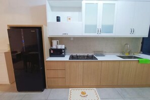 Eine Küche mit weißen Schränken, einem schwarzen Kühlschrank, einem Gasherd und einem Spülbecken.