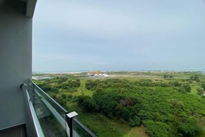 A balcony with a view of a green landscape and a distant building. - Atlantis Residence by Jeffery Lam Home Management (Melaka)