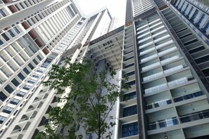 A high-rise building with multiple floors, balconies, and a tree in the foreground. - Atlantis Residence by Jeffery Lam Home Management (Melaka)