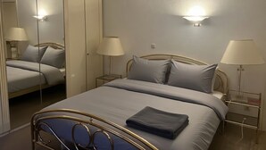 Un dormitorio con cama, lámparas de noche, armario y espejo.