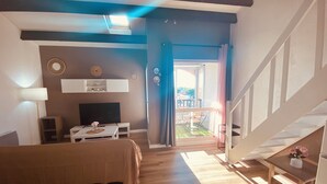 Ein gemütliches Wohnzimmer mit Bett, Fernseher und Balkon mit Aussicht.