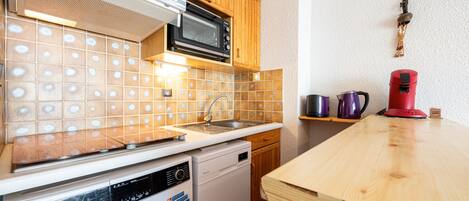 Una cocina compacta equipada con microondas, lavavajillas y lavadora.