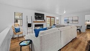 Una sala de estar moderna con chimenea, un sofá grande, una mesa de comedor y un televisor.