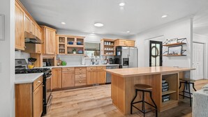 Una cocina moderna con armarios de madera, una isla central y un refrigerador empotrado.