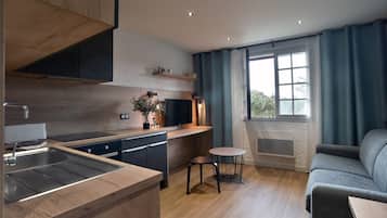 Cozinha moderna com armários de madeira, máquina de lavar louça embutida e uma janela grande com cortinas.