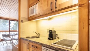 Une cuisine dotée de meubles en bois, d’un plan de travail en granit, d’un four à micro-ondes encastré, d’une machine à café et d’un lave-vaisselle.
