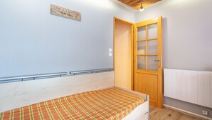 Une chambre avec un lit simple, une porte en bois, un radiateur blanc et une citation inspirante sur le mur.