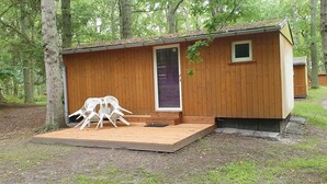 Una cabaña de madera con un pequeño porche, una puerta y una ventana.