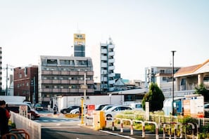 A parking lot with cars, a building with multiple floors, and a clear sky. - JS xiaozhai・Hoshishiro 2C (Osaka)