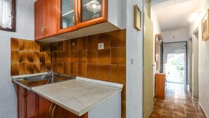 A kitchen with brown tiles, a sink, and wooden cabinets. - Nice apartment in Porec with WiFi (Porec)
