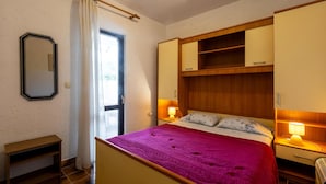 A bedroom with a bed, bedside lamps, a mirror, and a window. - Nice apartment in Porec with WiFi (Porec)