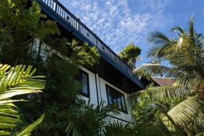 Een gebouw met een balkon met uitzicht op weelderige begroeiing en een heldere lucht.