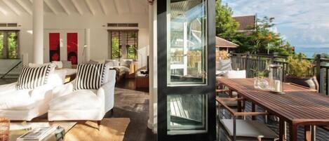A modern living area with a sofa, a wooden table, and a large glass door leading to an outdoor deck.