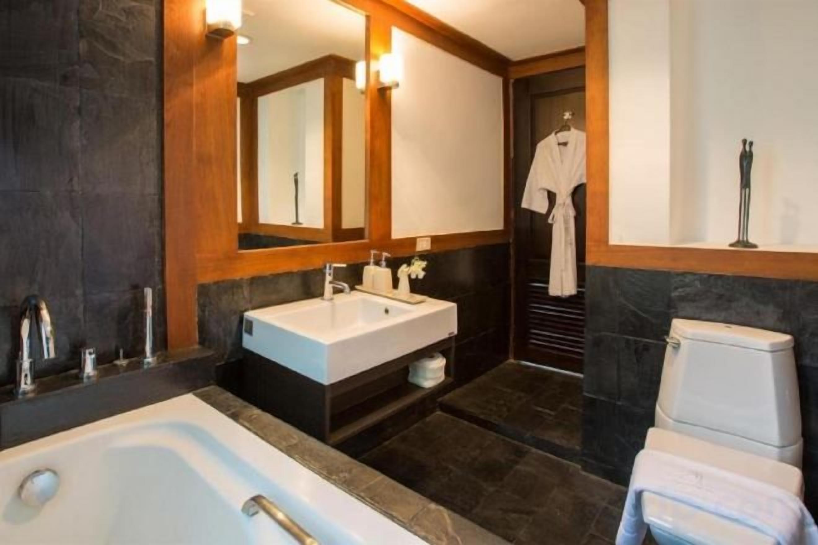 A modern bathroom with a bathtub, double sink, and a large mirror.