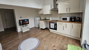 Een kleine keuken met een magnetron, oven en spoelbak.