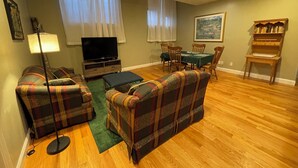 A living room with a sofa, a TV, a dining table with chairs, a lamp, and a bookshelf. - Quiet spacious apartment  sleeps 4. 1br plus den. (Albany)