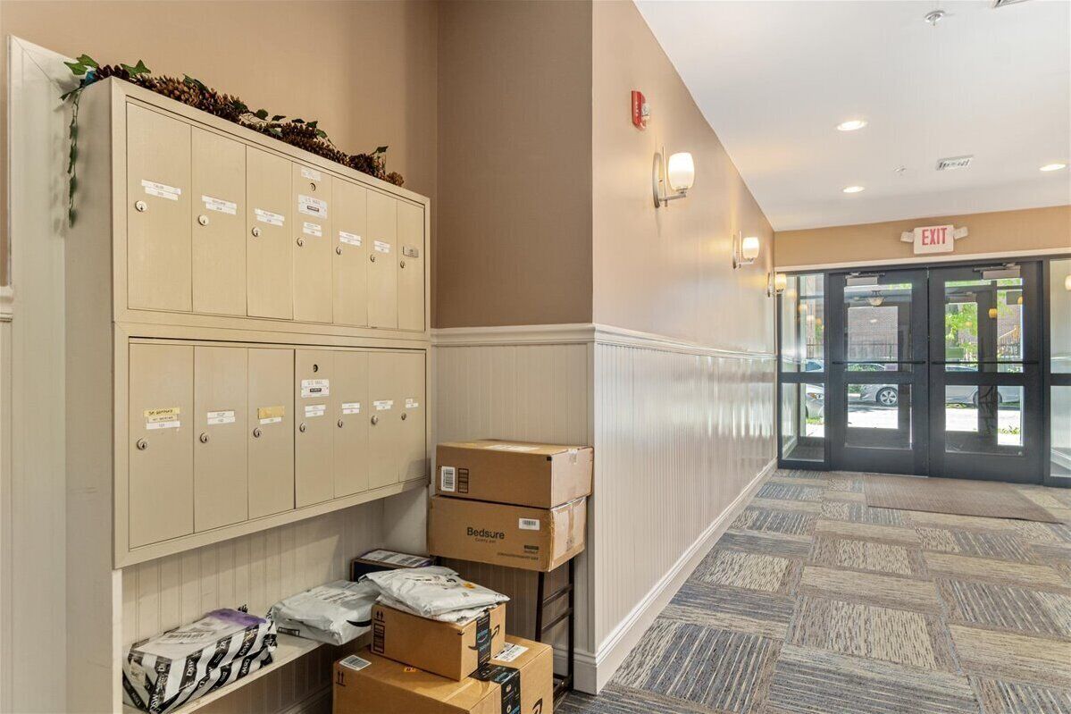 A hotel lobby with beige lockers, a carpeted floor, and an exit door.
