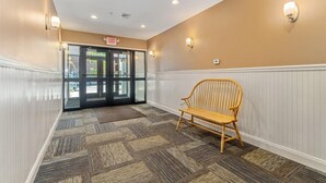 A hallway with a wooden bench, a glass door entrance, and a sign indicating an exit. - Quiet spacious apartment  sleeps 4. 1br plus den. (Albany)