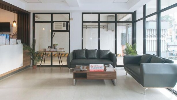 A modern reception area with a sofa, a coffee table, and a reception desk. - RedDoorz @ Traveler Inn Matina (Davao City)