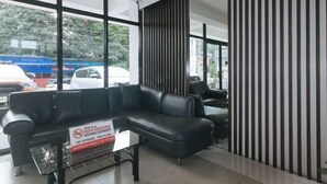 A modern indoor area with a black leather sofa, a striped partition, and a no-smoking sign. - RedDoorz @ Traveler Inn Matina (Davao City)