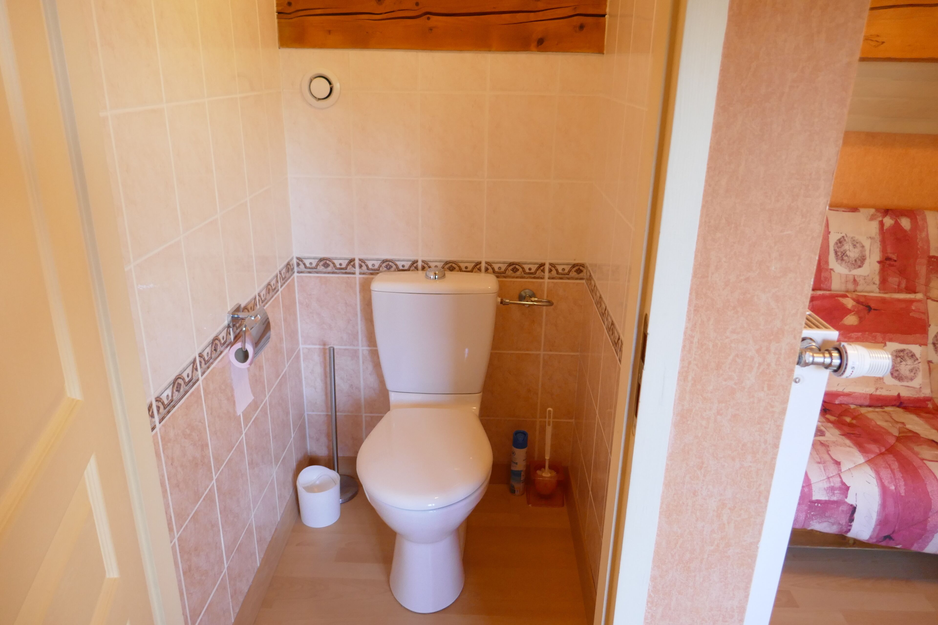 Ein kleines, kompaktes Badezimmer mit Toilette, Bidet und Toilettenpapierhalter.