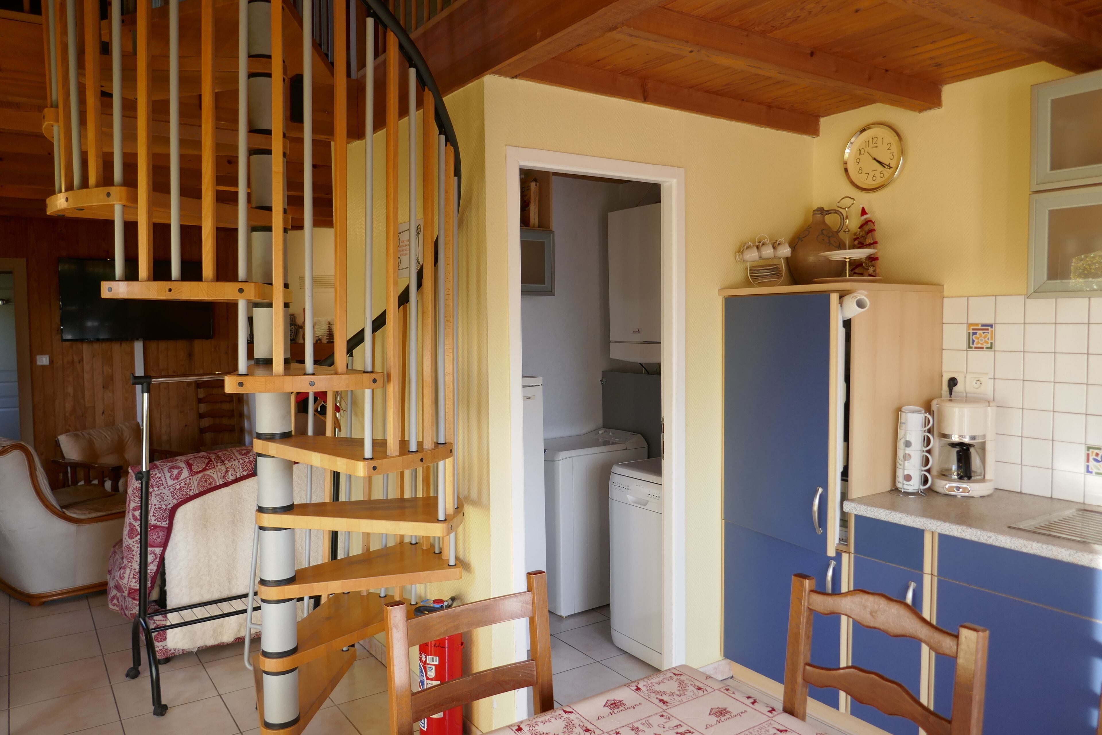 Eine Küche mit einer Wendeltreppe, einem Essbereich mit Stühlen und einem Kühlschrank.