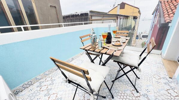A balcony with a dining table, chairs, and a view of a swimming pool.
