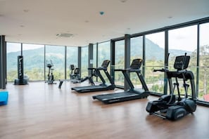 A gym with various exercise equipment, large windows, and a view of the outdoors. - Enclave Nature Suites Bukit Tinggi by BYON (Bentong)