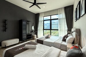 Quarto de hotel com duas camas, um ventilador de teto, uma janela grande com vista para as montanhas, um guarda-roupa e uma mesa de cabeceira.