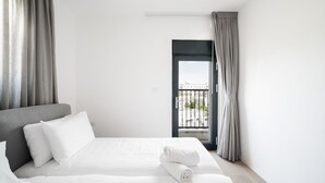 A hotel room with two beds, a balcony with a view, and grey curtains. - Penthouse - Four Bedroom Apartment, Sleeps 19 (Jerusalem)