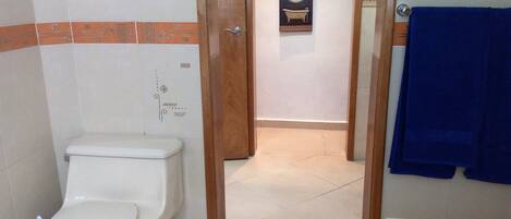 Une salle de bain avec des toilettes, un espace douche et une serviette bleue accrochée au mur.