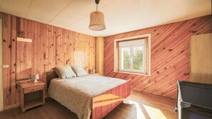 A wooden-paneled bedroom with a bed, bedside table, lamp, and a window with a view. - 3 bedroom stunning home in Plougasnou (Plougasnou)
