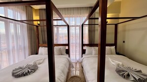 Una habitación con dos camas, cada una con dosel, y vistas de la ciudad a través de amplios ventanales.