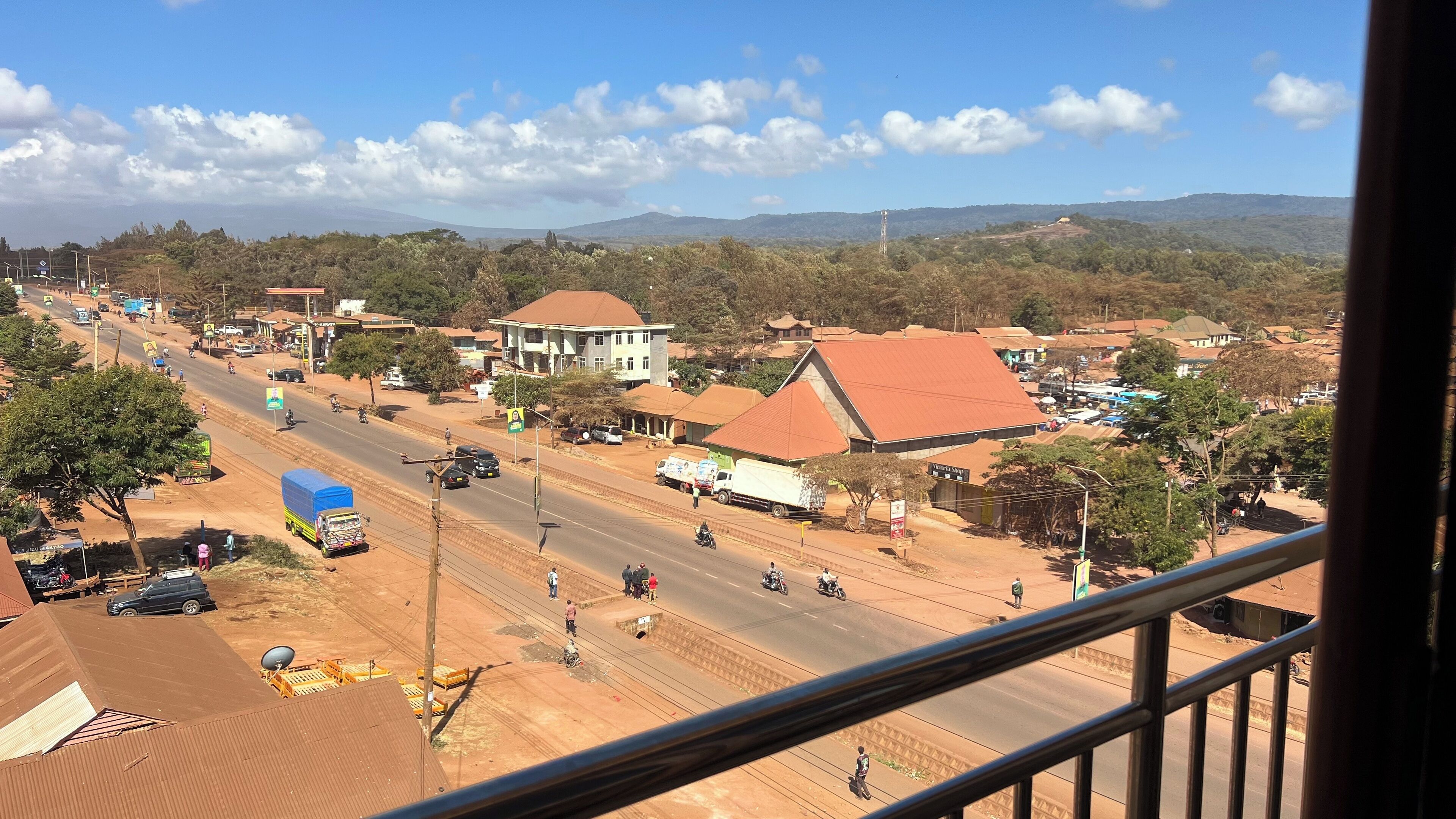 A town with a main road, buildings, and a mountainous backdrop.