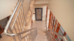 Una escalera moderna con barandillas de metal, suelo de mármol y paneles de pared de madera.