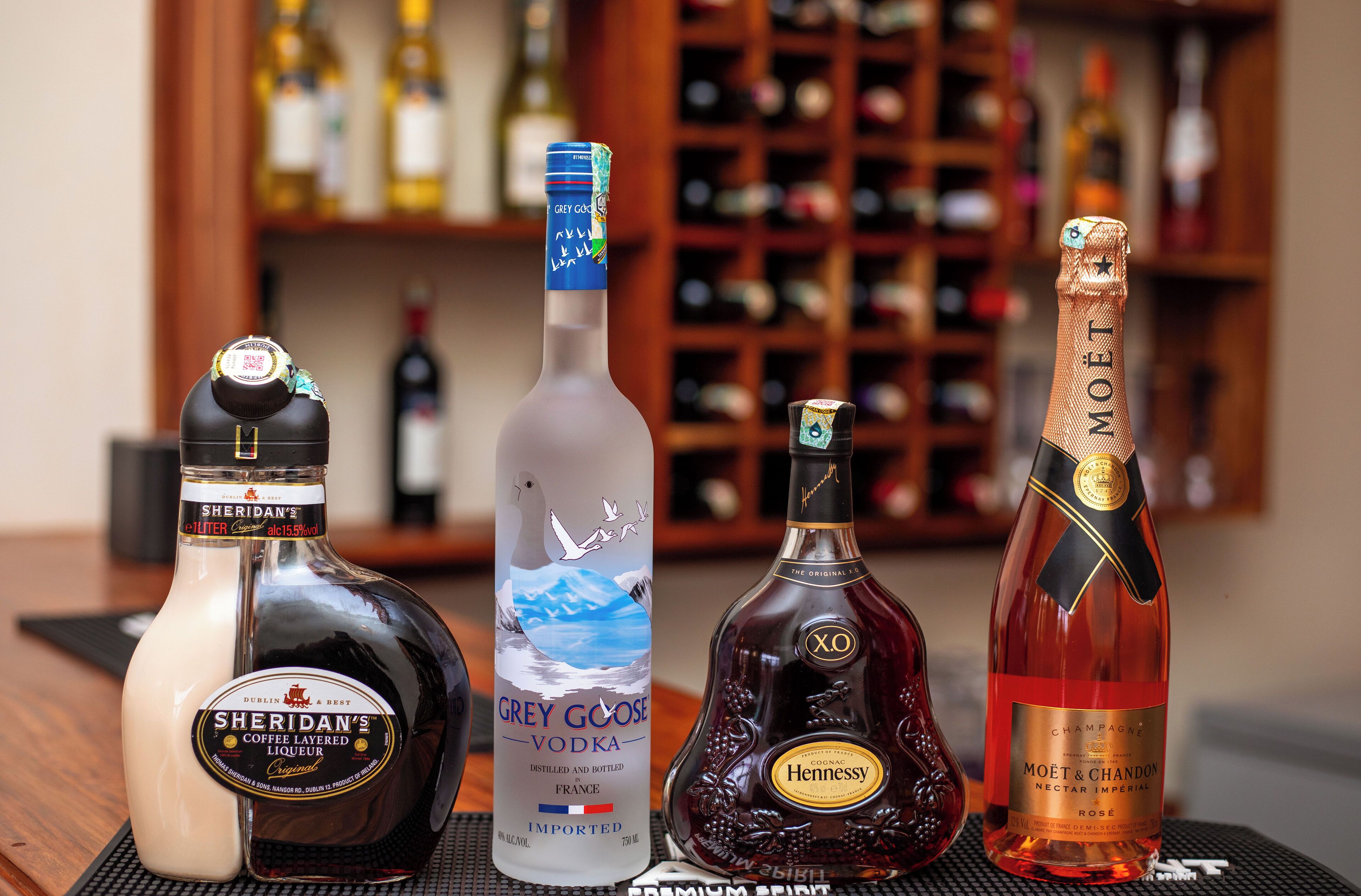 Four bottles of liquor on a table with a blurred background of shelves.