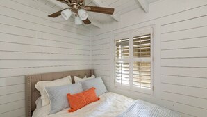 A bedroom with a bed, a ceiling fan, and a window with shutters. - 3-bedroom Lake Martin, AL cabin in cool Equality with WiFi, AC (Equality)