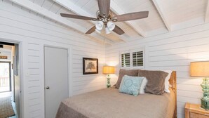 A bedroom with a bed, a ceiling fan, a door, and a small table with a lamp. - 3-bedroom Lake Martin, AL cabin in cool Equality with WiFi, AC (Equality)