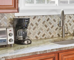 A kitchen with a coffee maker, a toaster, and a stainless steel faucet.