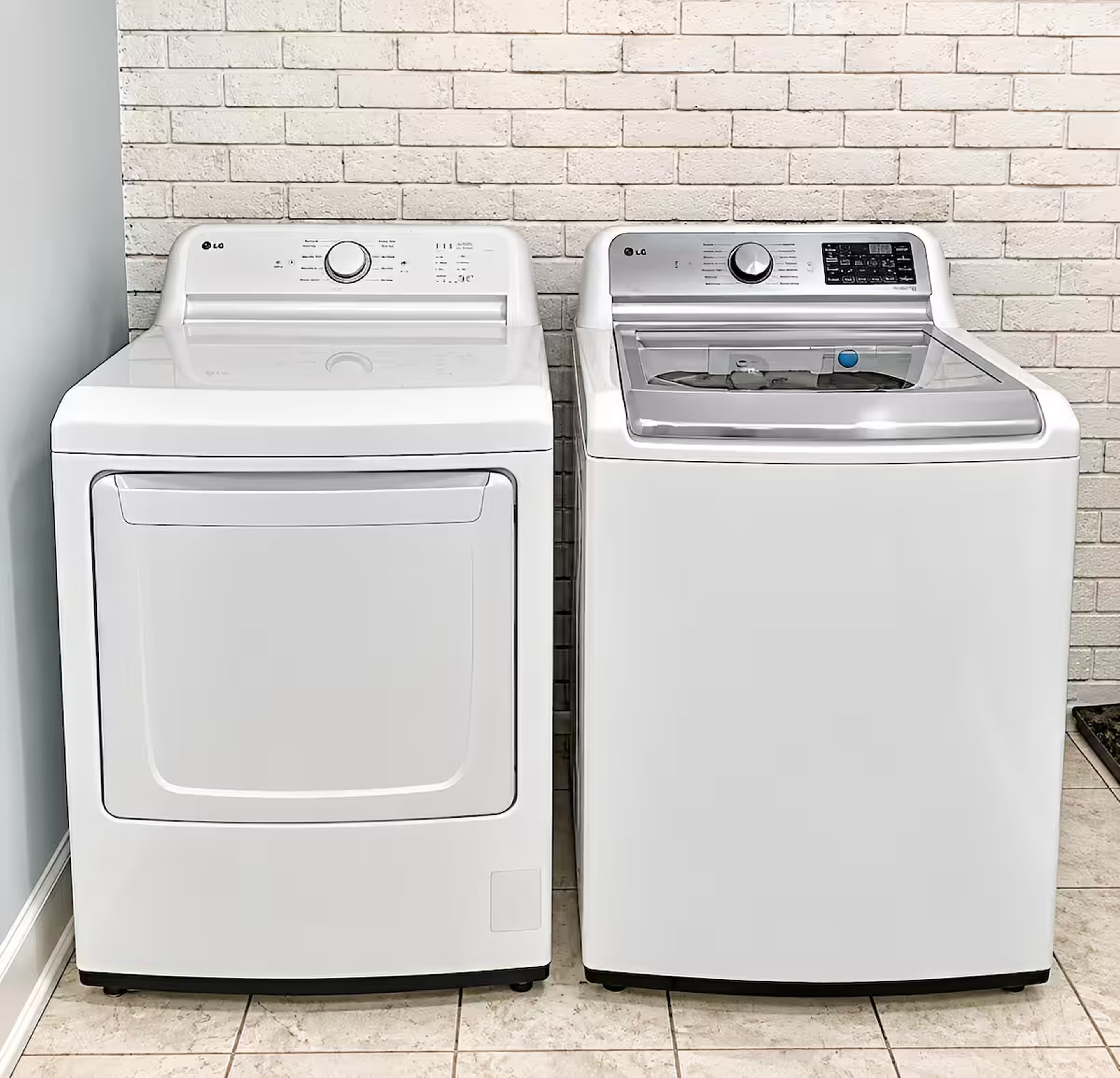 Twee witte wasmachines met een frontlaadmechanisme staan naast elkaar tegen een witte bakstenen muur.