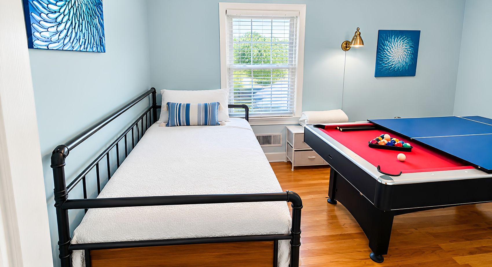 Un dormitorio con cama, mesa de billar y ventana con persianas.