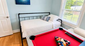 Un dormitorio con mesa de billar, cama y ventana con persianas.