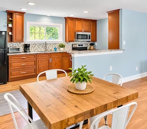 A kitchen with wooden cabinets, a microwave, and a dining table with chairs.
