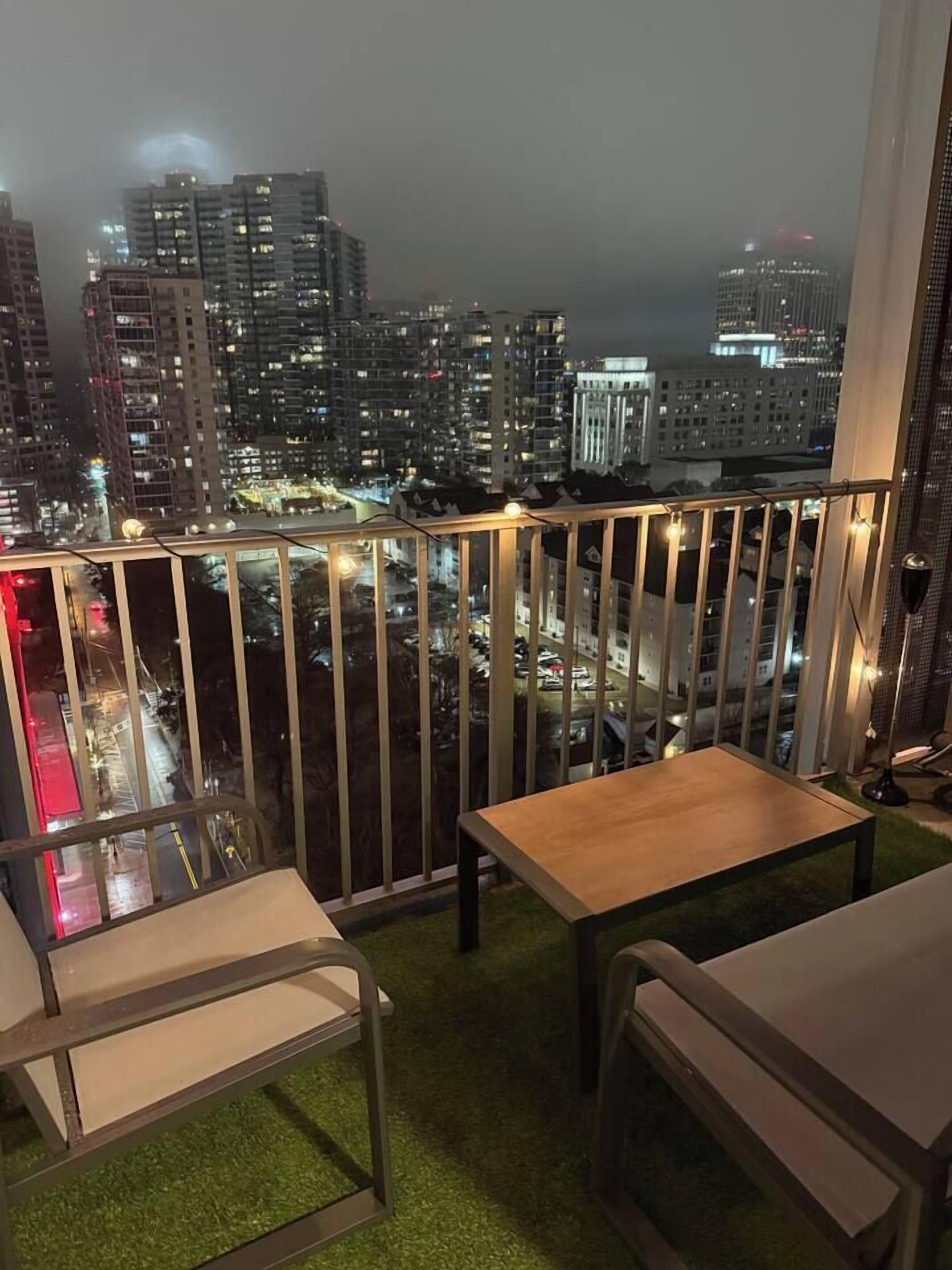 Uma varanda com vista para um horizonte urbano noturno, com vários edifícios altos.
